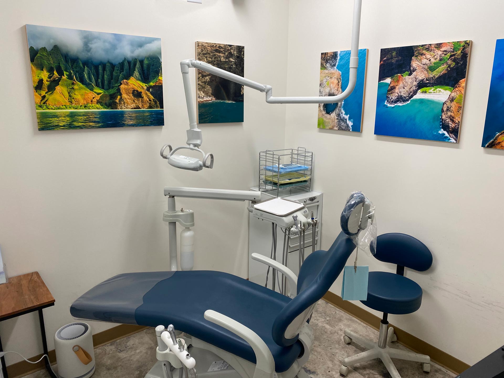 The image shows a dental office interior with a chair, dental equipment, and artwork on the wall.
