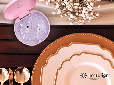 The image displays a table setting with various plates, bowls, and a tin container for holding toothbrushes, set against a backdrop of a wooden surface with decorative elements and a watermark indicating Invisalign .