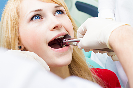 A young woman receiving dental care, sitting in a dentist s chair while being attended to by a dental professional.
